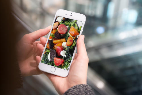 1 mujer sostiene móvil con imagen de comida